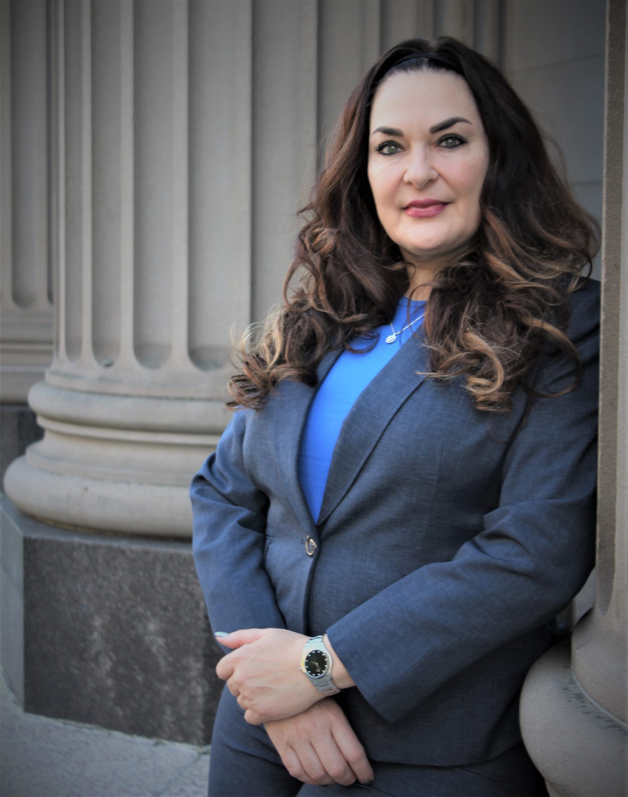 A woman in a suit leaning against a wall.